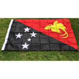Papua New Guinea flag in printed polyester laid flat on grass: black and red diagonal, white stars, yellow bird of paradise