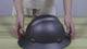 Black carbon-pattern full-brim hard hat on a bench: hands turn it over to show the harness, the headband and the adjuster inside.