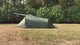 Green two-person tent pitched on dry grass, filmed in a slow walk-round, including the porch flap held up on red poles.