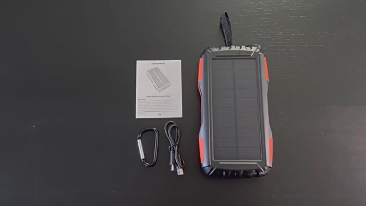 Black and orange rugged solar power bank up close: the solar panel face, the end torch switched on, the four charge lights and the ports, then charging a tablet and a phone at the same time.
