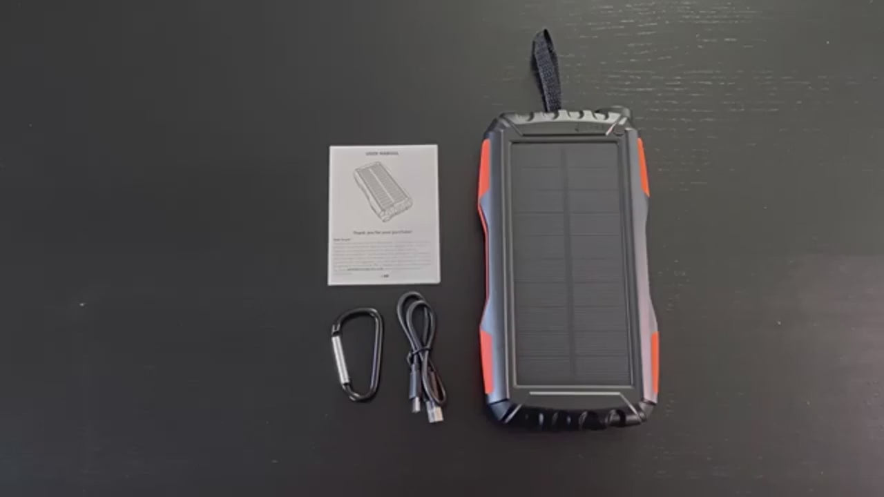 Black and orange rugged solar power bank up close: the solar panel face, the end torch switched on, the four charge lights and the ports, then charging a tablet and a phone at the same time.
