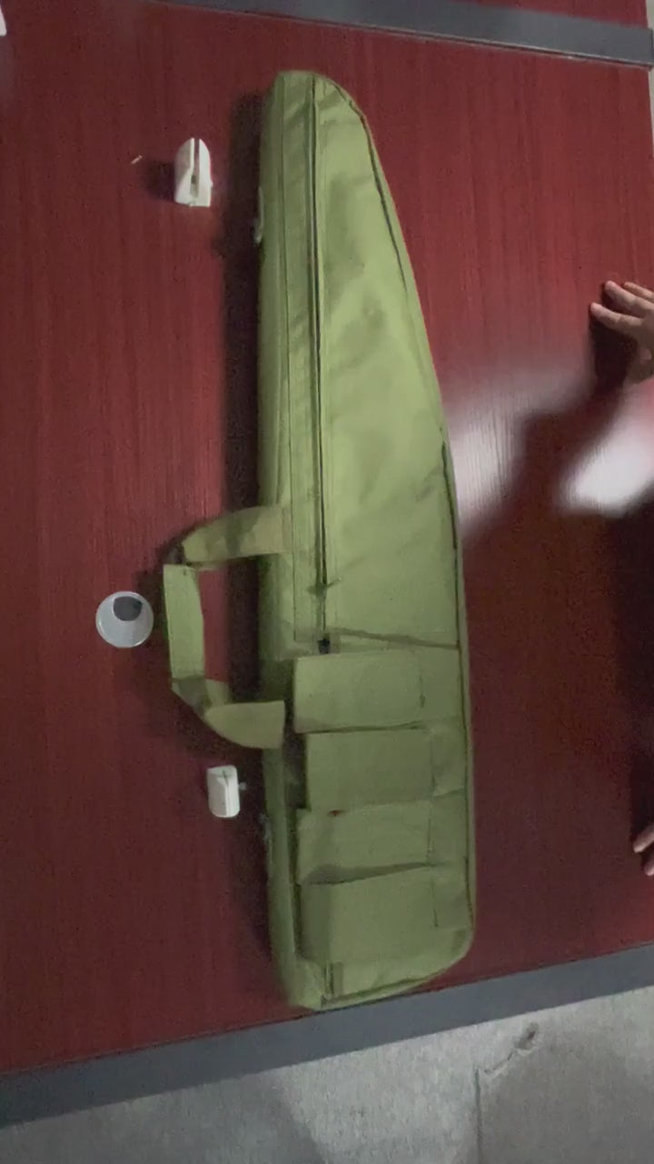 Green padded long carry case laid on a table, its straps and front pouches shown, then unzipped full length to show the egg-crate foam lining inside, empty.