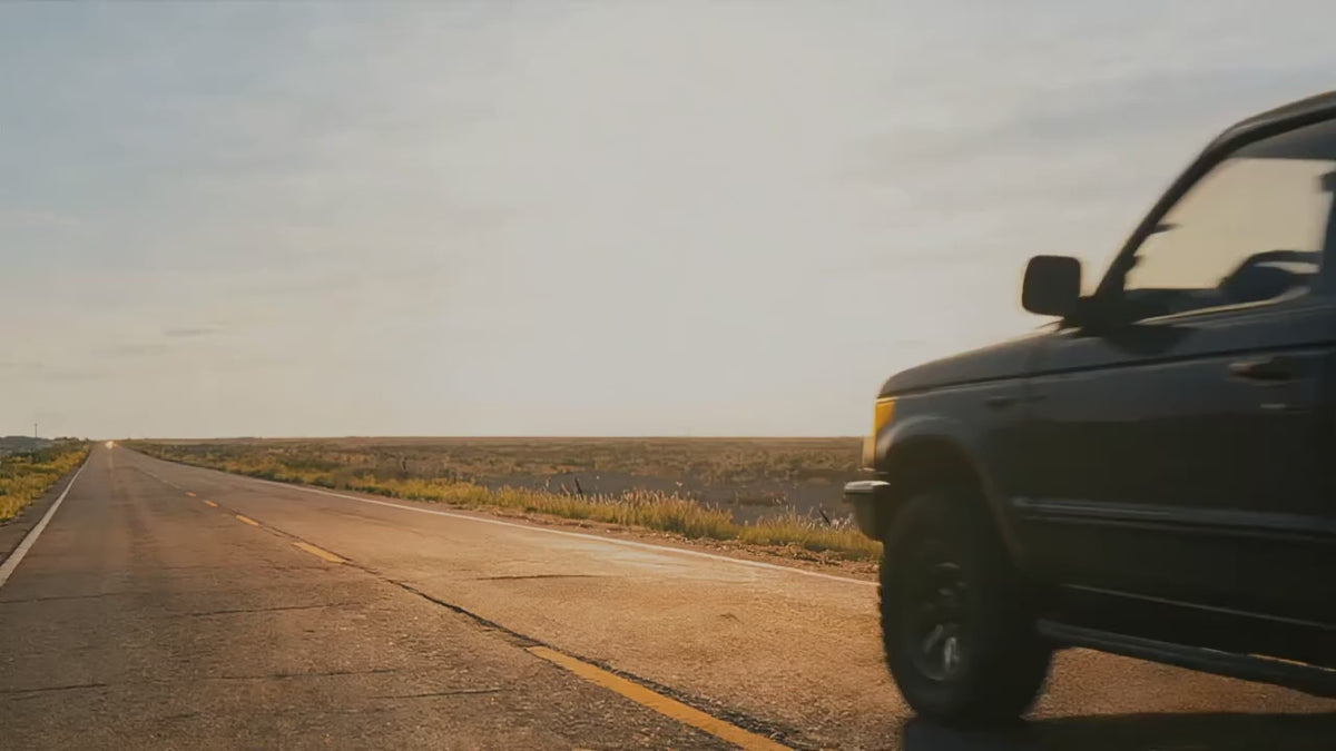 A pickup on an outback road at sunset, then the red GOOLOO A3 pack taken out, its clamps fixed to the battery under the bonnet, the key turned, and the truck driving off.