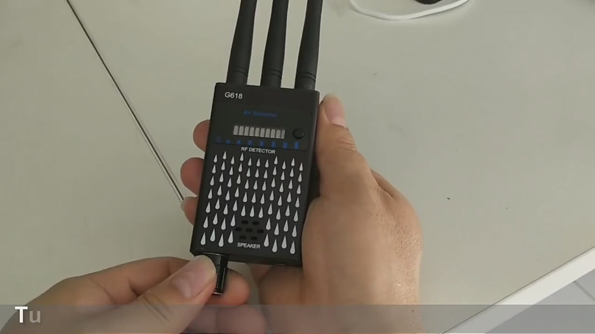 Black G618 detector held in the hand: the power knob turned, the LED meter climbing, and the detector picking up a phone's signal.