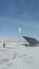 H2000 vertical wind turbine turning on its mast beside a solar array on a snowy plain