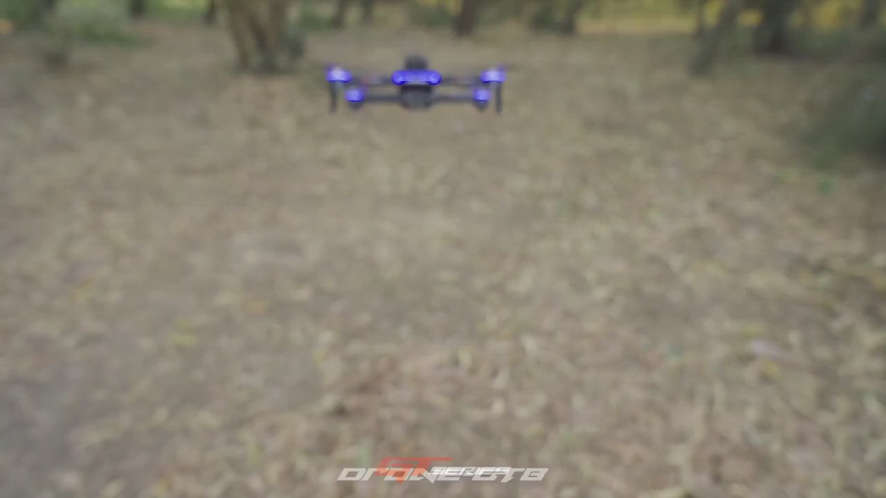GT8 drone flying towards the camera; close-ups of a brushless motor, the camera and the screen remote; the view from its front and downward cameras; the remote's screen showing the live picture; the drone holding a low hover and stopping short of a tree; ending with it landing on an open hand.