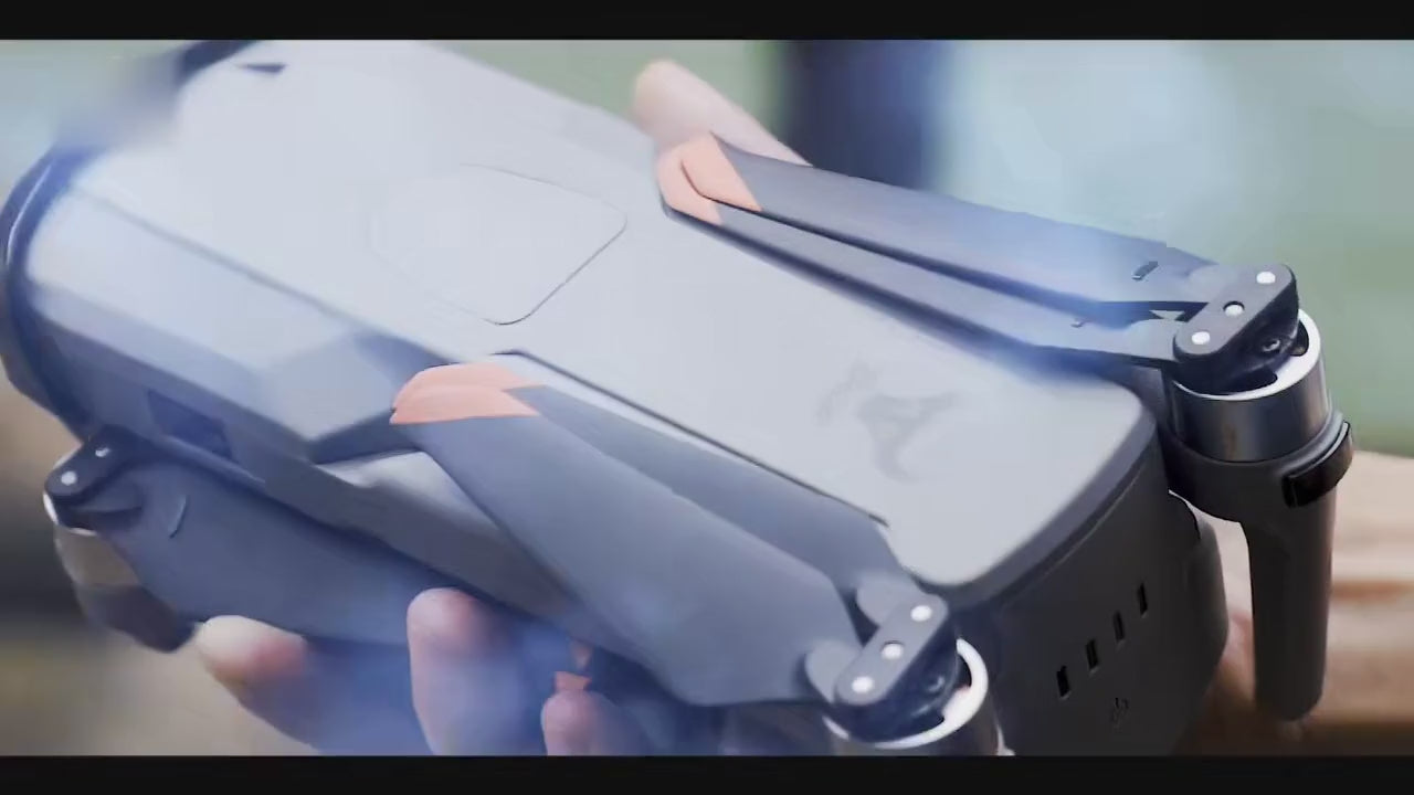 SG909MAX folded in the hand and unfolding; a pilot at a waterfall and on a lakeside rock with the touch-screen remote; close-ups of the three-axis gimbal camera and the remote showing the live picture; the drone flying past a waterfall, over a lake, above the clouds and along a rocky coast; ending with its return-home path to a landing pad.