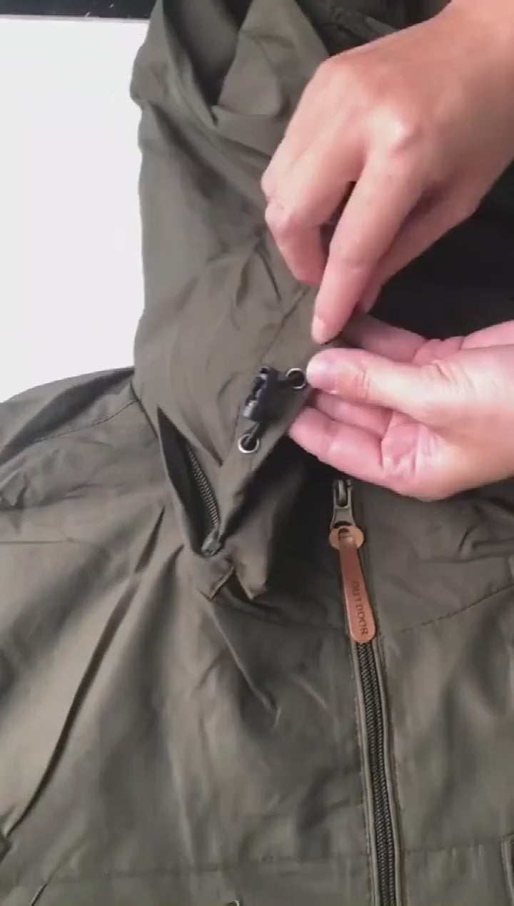 Olive green windbreaker laid flat: the hood and collar, the zip pulls, the chest and hand pockets, the cuff, and water beading off the fabric.