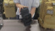 Black MOLLE water bottle pouch on a bench: the zip opened, a bottle slid in, then the pouch strapped onto a backpack's webbing.