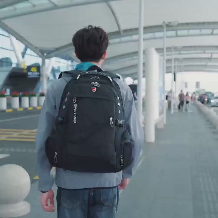 Man wearing the black anti-theft backpack through an airport, water beading on the fabric, then the zip pulls brought together, the laptop compartment opened and the inside pockets filled.