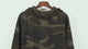 All-over green camo fleece hoodie shown front and back, then close-ups of the ribbed cuff, the hem and the soft fleece lining.