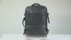 Black expandable laptop backpack on a table: the padded back and straps, then the expansion zip opened out and clothes packed into the main compartment.