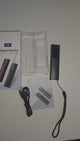 Handheld T15 detector taken from its box, switched on, and its red light used to sweep a room for camera lenses.