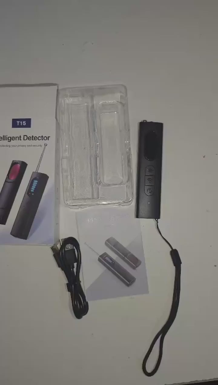 Handheld T15 detector taken from its box, switched on, and its red light used to sweep a room for camera lenses.