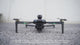 XT606 drone on the ground, the screen remote's buttons pressed, then the drone lifting off and hovering beside a building.