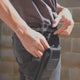 Phone holster worn on a belt, seen from behind: a phone slid into the pouch and the flap closed over it.