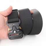 Black webbing belt held in one hand, showing the quick-release buckle and the coiled webbing