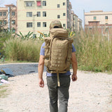 Man walking down a gravel track wearing the tan tactical backpack