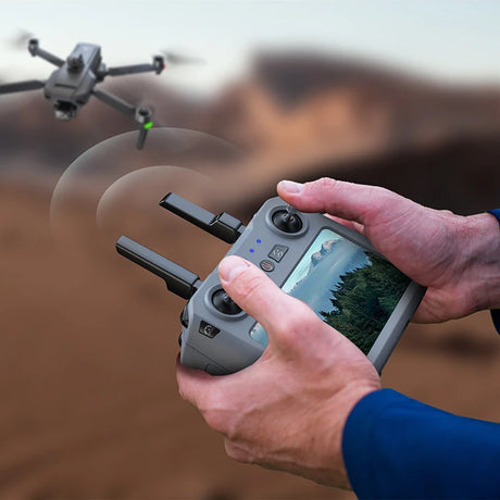 Pilot holding the SG909MAX touch-screen remote with the drone flying beyond