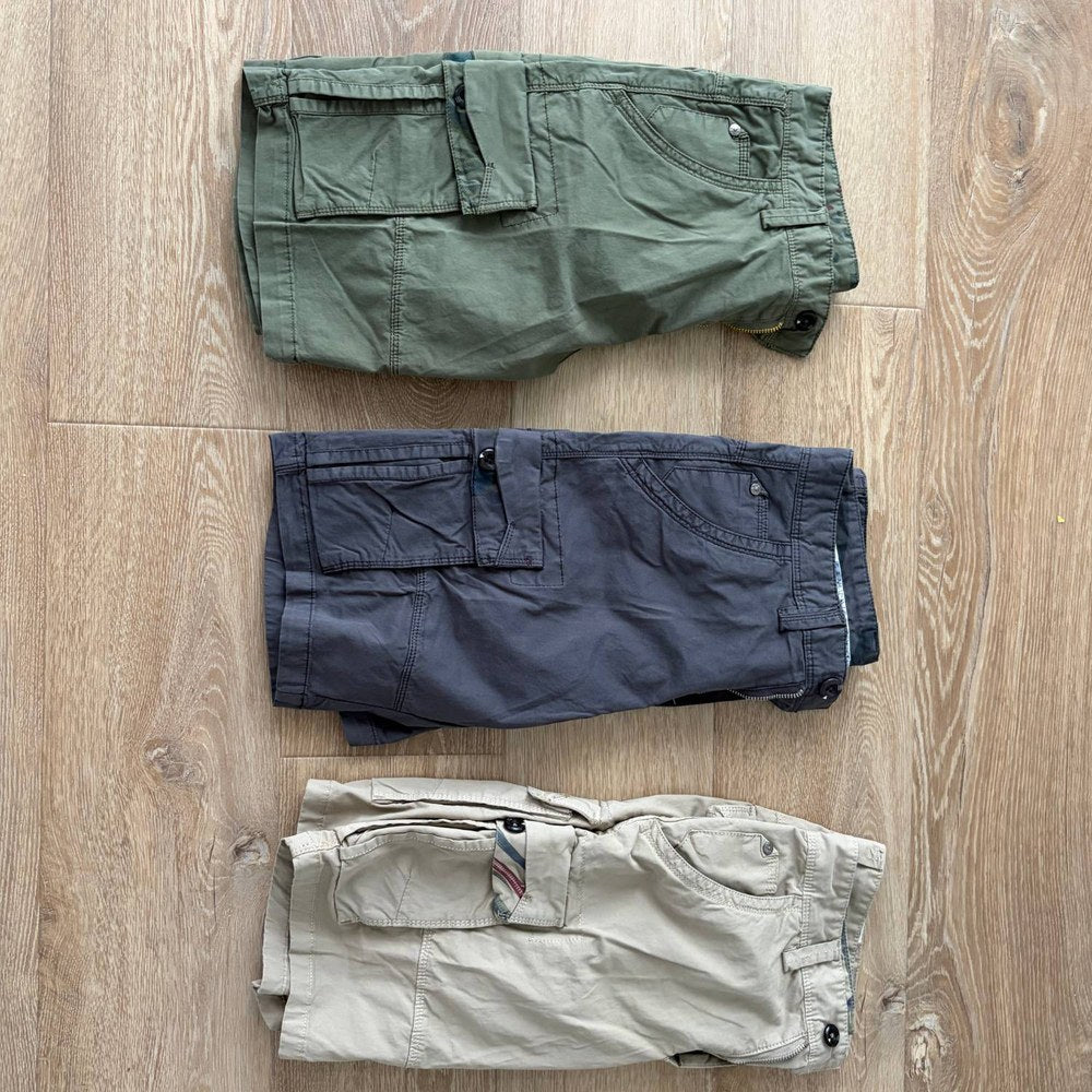 Customer photo of three pairs as delivered: Army Green, Dark Grey and Khaki six-pocket cargo shorts folded flat on a timber floor