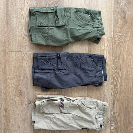 Customer photo of three pairs as delivered: Army Green, Dark Grey and Khaki six-pocket cargo shorts folded flat on a timber floor