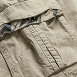 Close-up of a bellows cargo pocket on the khaki RELAX shorts with the flap lifted to show the camouflage print underneath