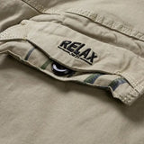 Close-up of the RELAX embroidered cargo pocket flap and its dark button on the khaki shorts