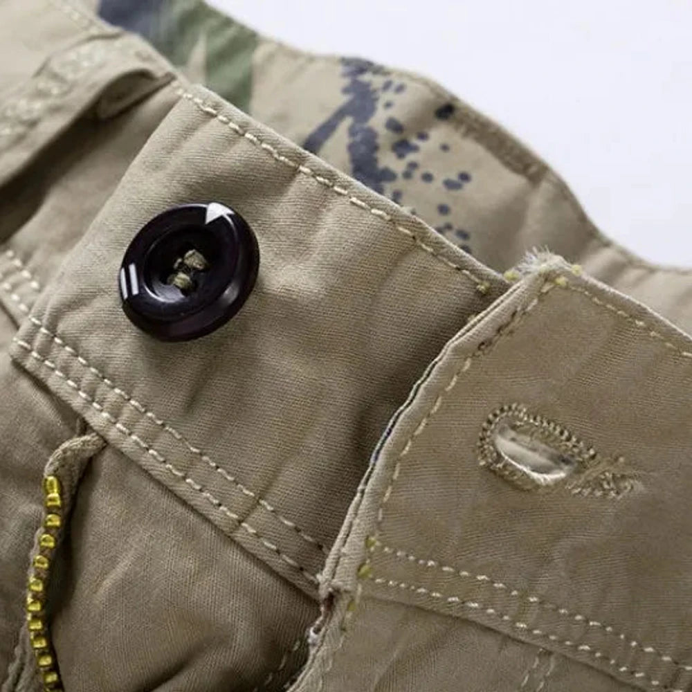 Close-up of the dark four-hole waistband button and stitched buttonhole on the khaki RELAX shorts, camouflage print showing on the inner waistband
