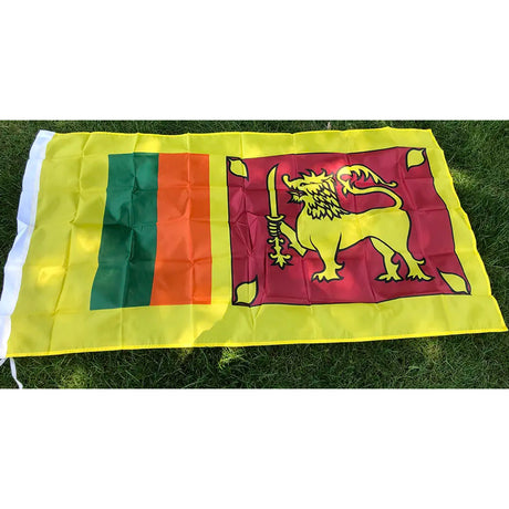 Sri Lankan flag in printed polyester laid flat on grass: gold lion with sword on maroon, green and orange bands, yellow edge