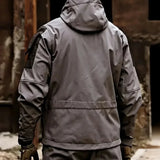 Back of the grey softshell jacket worn with the hood up and a black upper-sleeve panel; gloves and trousers not included