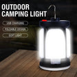 Tall camping lantern glowing on a timber table, with a wire hook on top