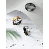 Black, gold and silver R10 smart rings laid on white marble and mesh fabric