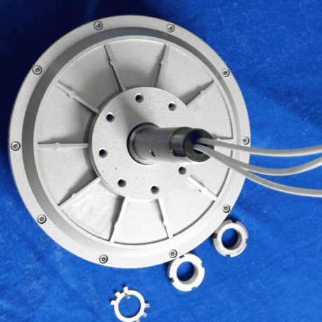 The ribbed cast-aluminium disc generator seen face on, with its bolted rim, cabled shaft and three lock rings laid out beside it.