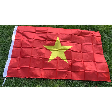 Vietnamese flag in printed polyester laid flat on grass: yellow star on red, white header strip at left