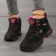 Women's ankle hiking boots in black with rose red trim, laced up and worn, side view of the rubber lug sole