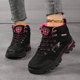 Women's ankle hiking boots in black with rose red trim, laced up and worn, side view of the rubber lug sole