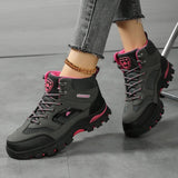 Grey and rose red hiking boots worn mid-stride, showing the lug sole and above-the-ankle height