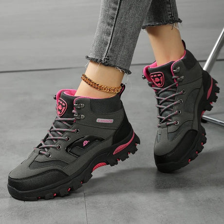 Grey and rose red hiking boots worn mid-stride, showing the lug sole and above-the-ankle height