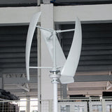 White three-blade X-series vertical-axis turbine test-mounted on a pole inside the factory, steel roof trusses behind - representative X-series photo.