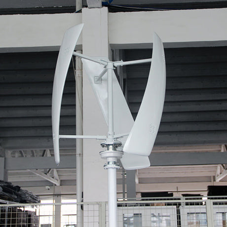 White three-blade X-series vertical-axis turbine test-mounted on a pole inside the factory, steel roof trusses behind - representative X-series photo.