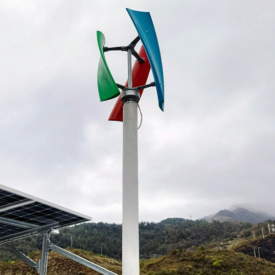 X-series turbine with green, red and blue blades on a tall pole beside a ground-mounted solar array on a hillside - supplier install photo; BushLine stocks white.
