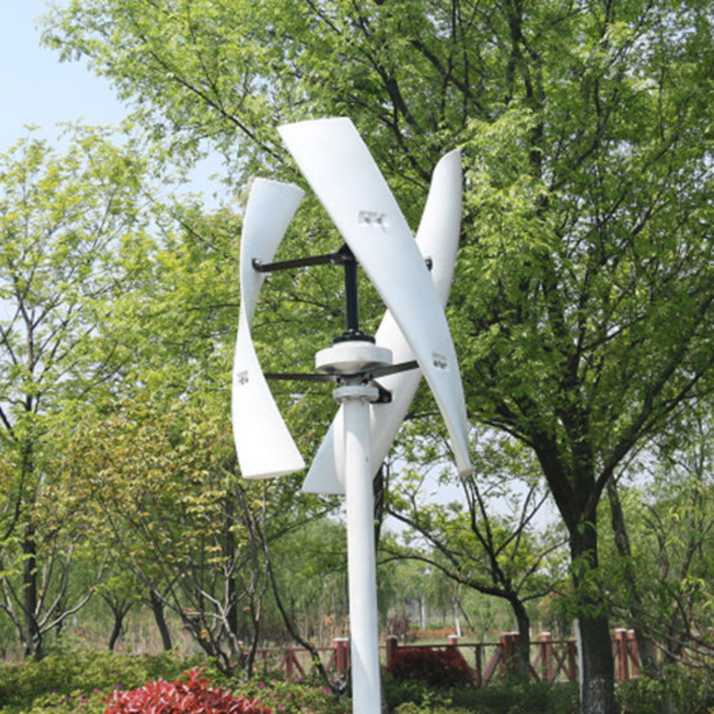 White three-blade X-series helical turbine pole-mounted in parkland with trees and a timber fence behind - representative X-series photo.