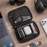 Pouch unzipped flat holding a car key, earbuds case, cards and a key ring