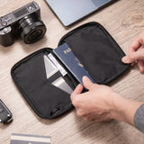 Hand sliding a passport into the open pouch next to the card pockets