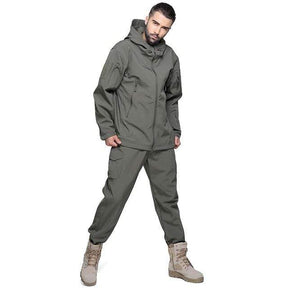 Grey-green softshell set, studio, hood down and one hand in a trouser pocket