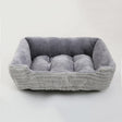 Grey bolster pet bed at an angle, showing the centre cushion tufted into three sections and the low front edge