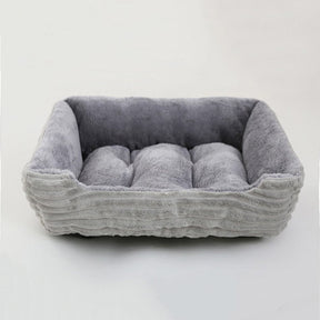 Grey bolster pet bed at an angle, showing the centre cushion tufted into three sections and the low front edge