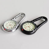 Silver and black carabiner clip watches side by side on a grey surface, luminous dials facing up